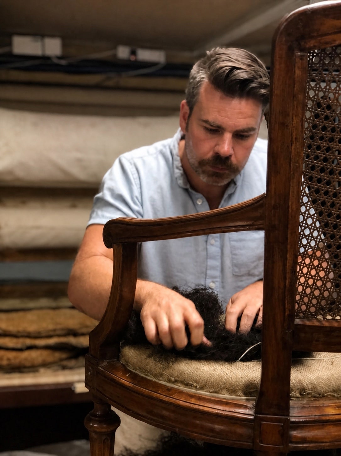 Paul re-upholstering an antique chair in the Sofarooms workshop